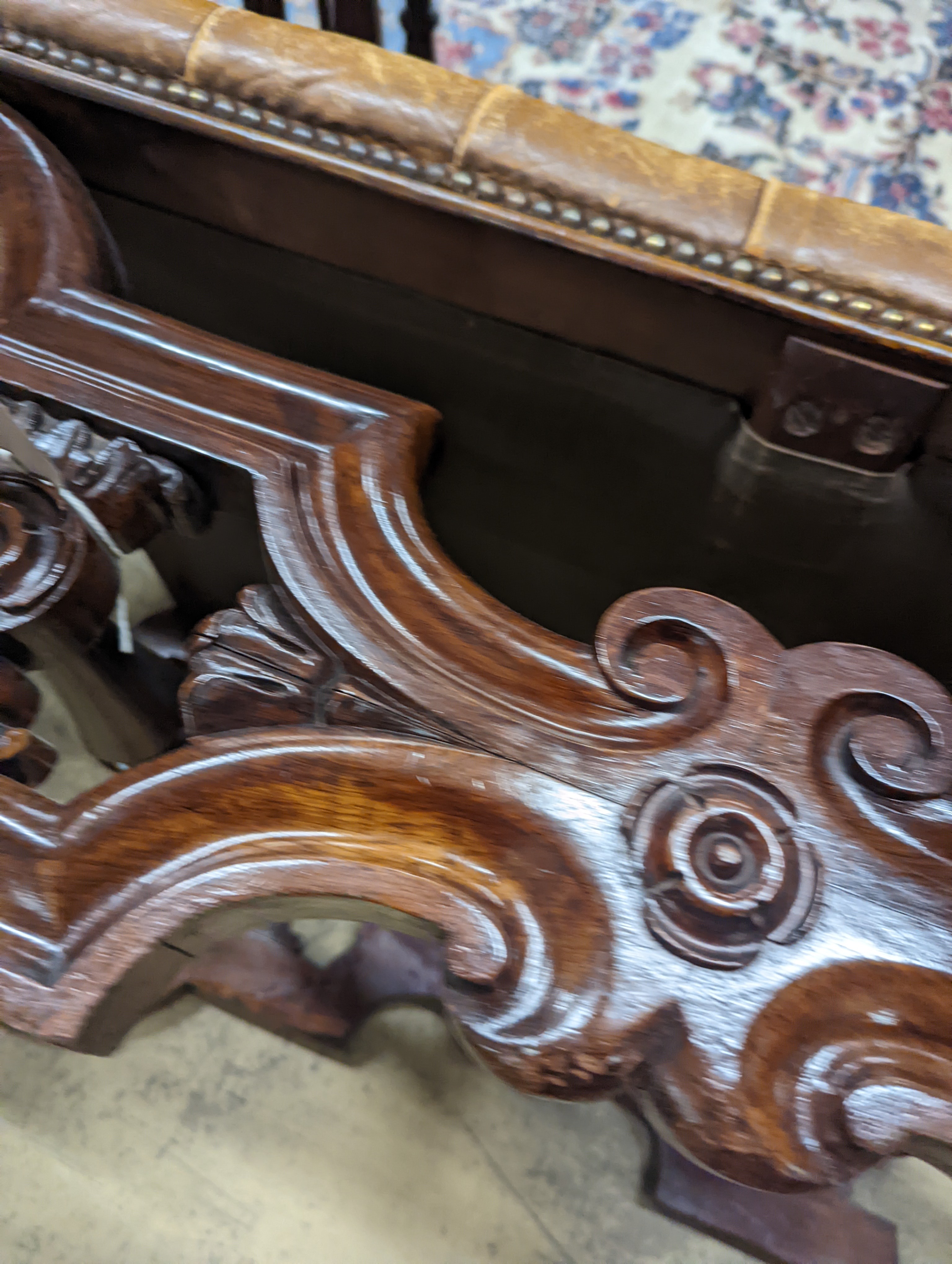 A Victorian carved X-framed rosewood footstool, upholstered in a buttoned brown leather, width 90cm depth 57cm height 42cm